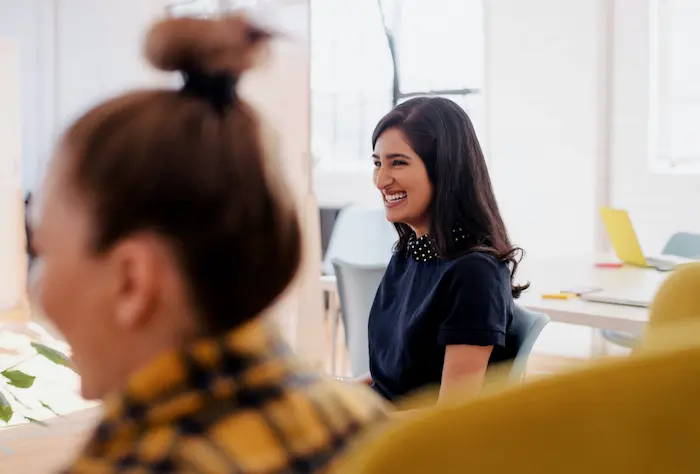 Deux femmes souriantes dans un bureau.